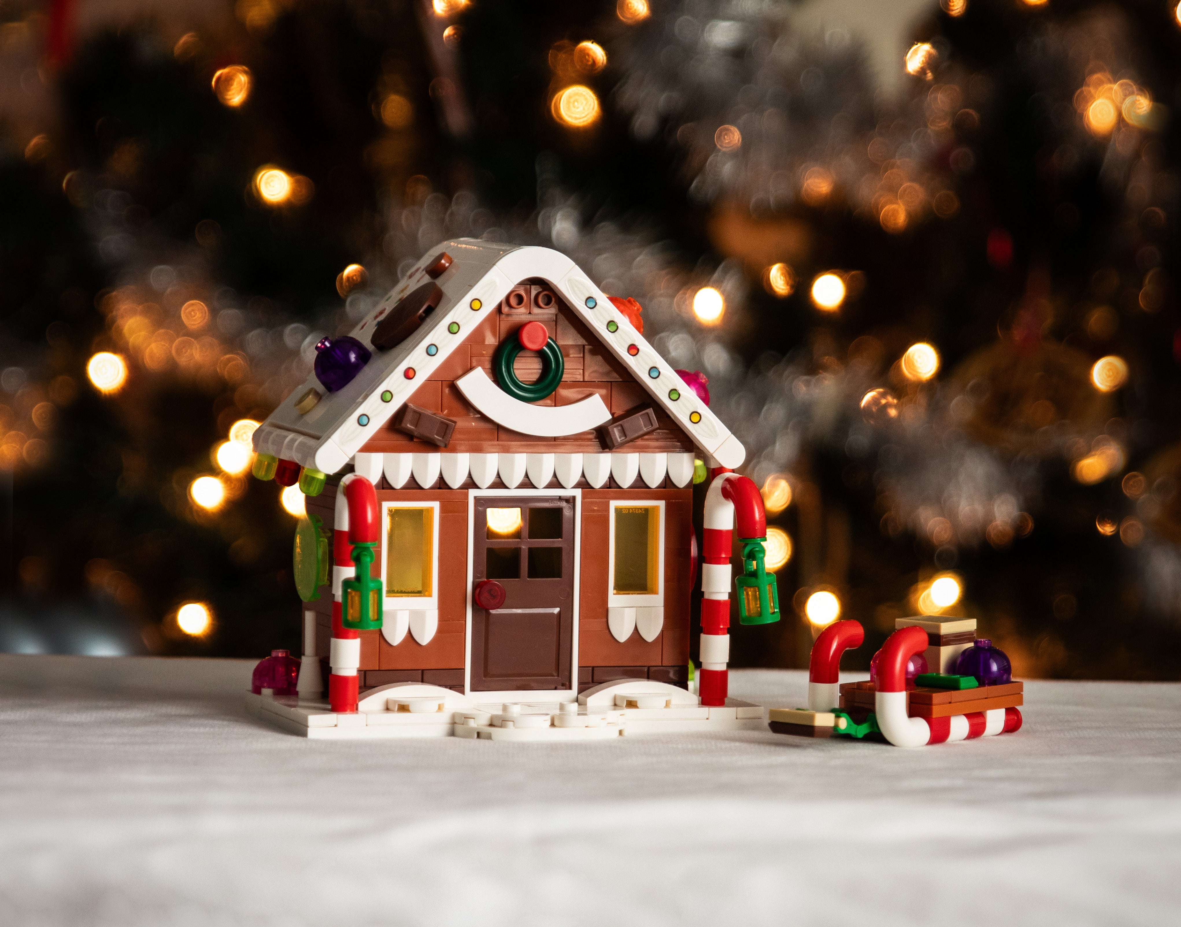 Decorative gingerbread house model with candy elements on a blurred festive background