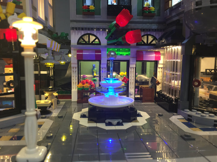 Close up of the LEGO Assembly Square set 10255 with the Brick Loot LED Light Kit installed. Even the fountain is illuminated!