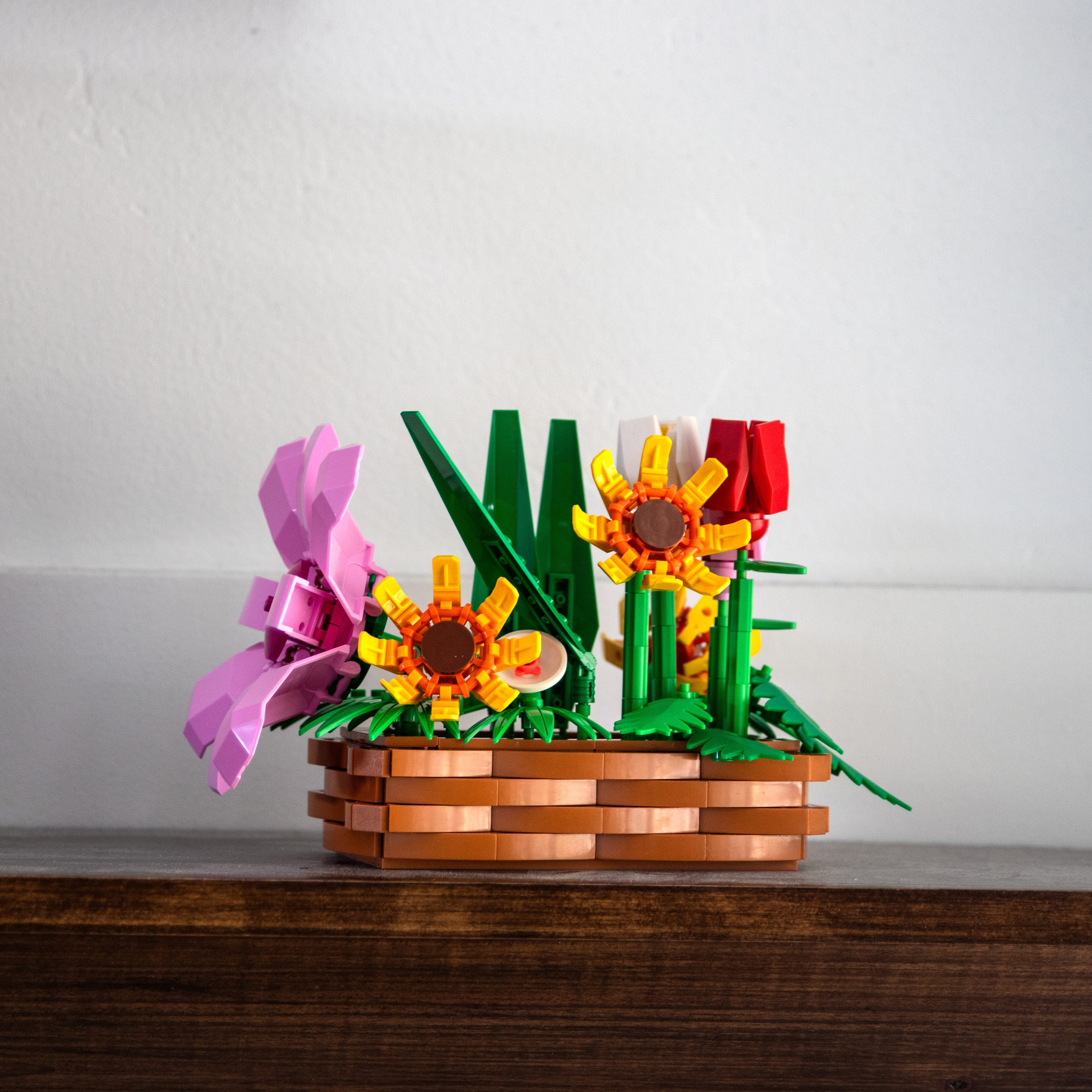 LEGO flower arrangement in a basket on a wooden surface with a white background